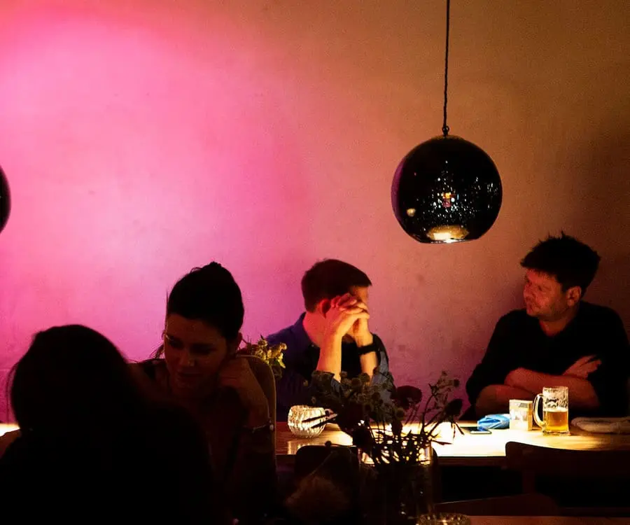 Dunkel beleuchtete Bar mit pinker Wandbeleuchtung und hängenden Lampen.