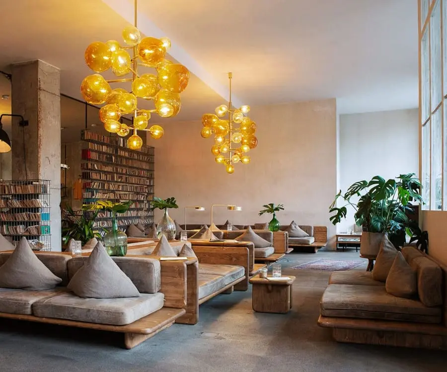 Moderne Hotel-Lobby mit Holzsofas, Pflanzen und runden gelben Lampen.